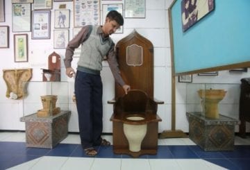 Muzeum toalet w Indiach mężczyzna prezentuje obiekt muzealny